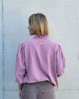 Blusa de algodón con cuello mao y volados, mangas largas con puños elásticos y corte holgado.