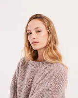 Buzo tejido a mano con lana, color rosa con motas de colores. Diseño oversized, largo entre la cintura y la cadera, con detalle de trenzas en las mangas.