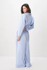 Pijama de algodón a rayas celestes y blancas, compuesto por una camisa de manga larga con botones y un pantalón largo de corte ancho.