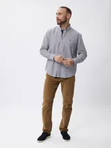 Camisa de manga larga con estampado de rayas verticales finas, cuello abotonado y cierre frontal con botones. Presenta un diseño clásico con detalle de logo bordado en el pecho.