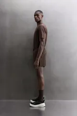 Short de running color marrón, confeccionado en tejido técnico elástico con forro interior. Cuenta con cintura elástica ajustable, bolsillos laterales con cierre de cremallera oculto y aberturas en las perneras.