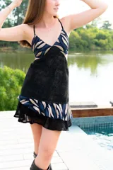 Vestido corto de diseño bicolor en tonos marrón, con top de escote en V en tela metalizada y falda fluida. Presenta aberturas laterales en la cintura, breteles finos cruzados en la espalda y ruedo con doble volado irregular.