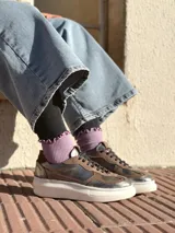 Zapatillas deportivas de cuero color peltre, con cordones negros y suela de goma blanca.