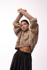 Sweater de tejido de punto grueso con diseño de rombos en relieve, cuello redondo y mangas largas amplias. Presenta una silueta relajada y holgada.