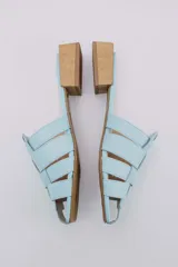 Mules de cuero celeste con diseño trenzado y taco de madera.