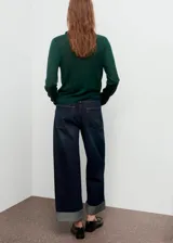 Jersey de punto fino en color verde oscuro, con cuello drapeado y manga larga. Presenta un diseño recto y ligero.