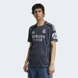 Camiseta de fútbol Adidas del Real Madrid, modelo segunda equipación temporada 25/26. Diseño azul oscuro con estampado efecto muaré y detalles metalizados plateados.