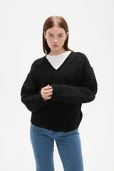 Sweater de punto color blanco, con cuello en V, manga larga y diseño holgado.