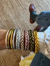 Pulsera de resina flexible con diseño trenzado y acabado brillante, con relleno de lámina metálica en tonos dorados, plateados y cobrizos.
