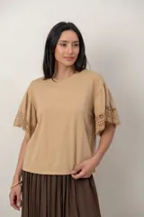 Remera de algodón color blanco, con cuello redondo y mangas cortas holgadas que presentan detalles de encaje broderie.