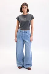 Pantalón wide leg de denim azul medio, de tiro medio con pinzas en la parte delantera y corte ancho en las piernas.