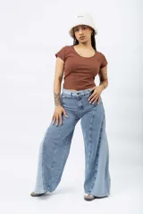 Jean wide leg azul claro con paneles de mezclilla de diferentes tonos y costuras diagonales.