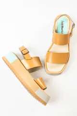 Sandalias negras de cuero con plataforma blanca y hebilla metálica.