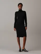 Vestido negro de lana merina, corte recto, largo hasta la rodilla, cuello alto y mangas largas.