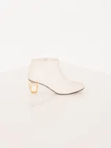 Bota de cuero color blanco con taco acrílico transparente y cierre lateral.