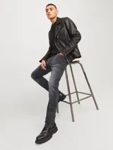 Jean de corte slim fit con tiro bajo, confeccionado en denim elástico de color gris oscuro con efecto lavado. Presenta diseño clásico de cinco bolsillos, cierre frontal con botón y costuras reforzadas.