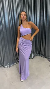 Vestido largo lila de un solo hombro con acabado brillante y diseño cut-out en la cintura.