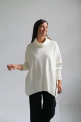Polerón de punto color crudo, con cuello alto tipo polera, corte holgado y mangas largas con puños acanalados.