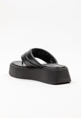 Sandalia tipo ojota con plataforma, confeccionada en material sintético color blanco. Presenta una tira ancha acolchada con detalle de costura central y diseño de separación para el dedo.