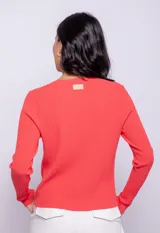 Top de tejido de punto color coral, con cuello redondo, mangas largas y cut outs frontales con botones metálicos.