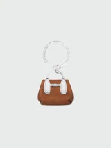Llavero Longchamp modelo Roseau, con dije en forma de mini cartera color marrón y herrajes plateados.