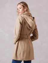 Gabardina trench de tejido repelente al agua en color beige. Presenta cuello con solapa ancha, cierre frontal con botones en tono carey, capucha desmontable y lazo de ajuste en la cintura. Incluye bolsillos laterales tipo ojal y forro interno a tono.