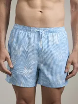 Short de baño con diseño estampado que combina rayas verticales y líneas onduladas en tonos celestes y blancos. Cuenta con cintura elástica con cordón ajustable.