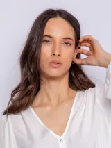 Camisa blanca de manga larga con escote en V y botones nacarados en la parte frontal.