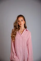 Camisa rosada con detalles de broderie en la parte delantera y mangas anchas.