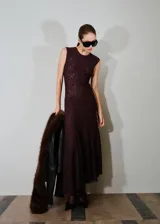 Vestido largo de encaje en color bordó, con diseño entallado, cuello redondo, sin mangas y bajo asimétrico con fruncido lateral. Incluye forro interior.
