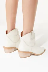 Botas de cuero vacuno color negro con caña baja bordada a tono, tacón bajo, punta alargada redondeada y suela cuadrada.