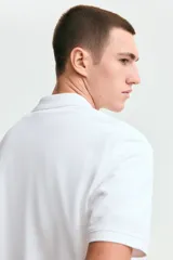 Remera polo blanca de manga corta en piqué de algodón, con cuello clásico y tapeta de dos botones.