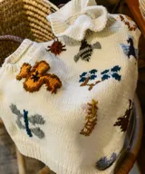 Chaleco de punto color marfil, con cuello alto estilo gorguera y bordados artesanales de insectos y elementos de la naturaleza en la parte delantera.