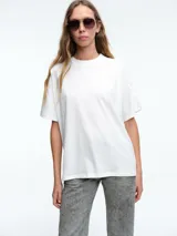 Camiseta de corte oversize, color blanco, con cuello redondo en tejido acanalado y mangas cortas.