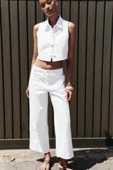 Pantalón blanco de jean con bordados calados en los laterales, de tiro medio y pierna ancha.