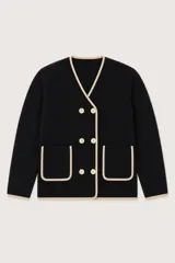 Saco de punto negro con diseño cruzado, cuello en V y ribetes en color beige. Presenta cierre frontal con botones claros, dos bolsillos delanteros aplicados y mangas largas.