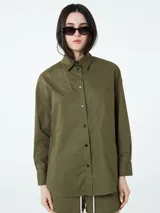 Conjunto compuesto por una camisa de manga larga con botones frontales y un short con cintura elástica y cordón ajustable, ambos en color negro.