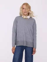 Sweater gris de tejido de punto con terminación en lurex y cuello camisero blanco.