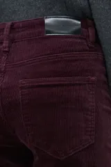 Pantalón de pana de corte recto y tiro medio, color ciruela, con detalle de tajo en el ruedo.