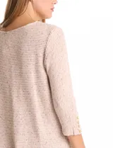 Buzo de tejido soft color beige con textura jaspeada, cuello redondo, mangas tres cuartos con detalle de botones en los puños y tajos laterales en el ruedo.