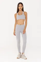 Top deportivo gris claro de poliéster y elastano, con espalda descubierta, breteles finos y banda elástica inferior.