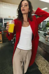 Abrigo largo de Zara confeccionado en mezcla de lana color rojo, con cuello de solapa, manga larga, bolsillos con solapa en el frente y cierre frontal de botones negros.