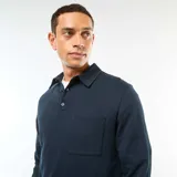 Buzo de manga larga color azul marino, con cuello tipo polo y tapeta de dos botones. Presenta un bolsillo de parche en el pecho.