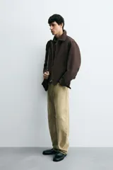 Cazadora cropped fit color marrón oscuro, confeccionada en tejido de algodón. Presenta cuello solapa, manga larga con puño abotonado, bolsillos de vivo en la cadera y un bolsillo interior. El bajo tiene elástico en la espalda y el cierre es frontal con cremallera.