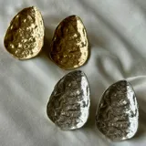 Par de caravanas con forma irregular, con textura martillada y acabado brillante.