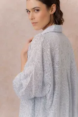 Camisa lila oversize de algodón con bordado floral calado tipo broderie, cuello camisero, manga larga y abotonadura frontal.