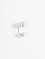 Broche dorado con dos perlas blancas de diferentes tamaños.