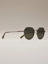 Lentes de sol con armazón geométrico octogonal de metal oscuro y detalles en marrón translúcido, cristales oscuros y puente metálico delgado.