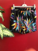 Short de baño Reef negro con estampado de flores abstractas en tonos violeta, naranja, amarillo y celeste.