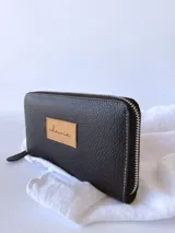 Billetera grande de cuero color negro, con cierre metálico y monedero interno.